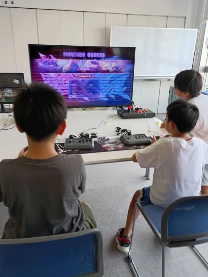 ゲーム交流会でコントローラーを持ってゲームに参加する子どもたちの後ろ姿