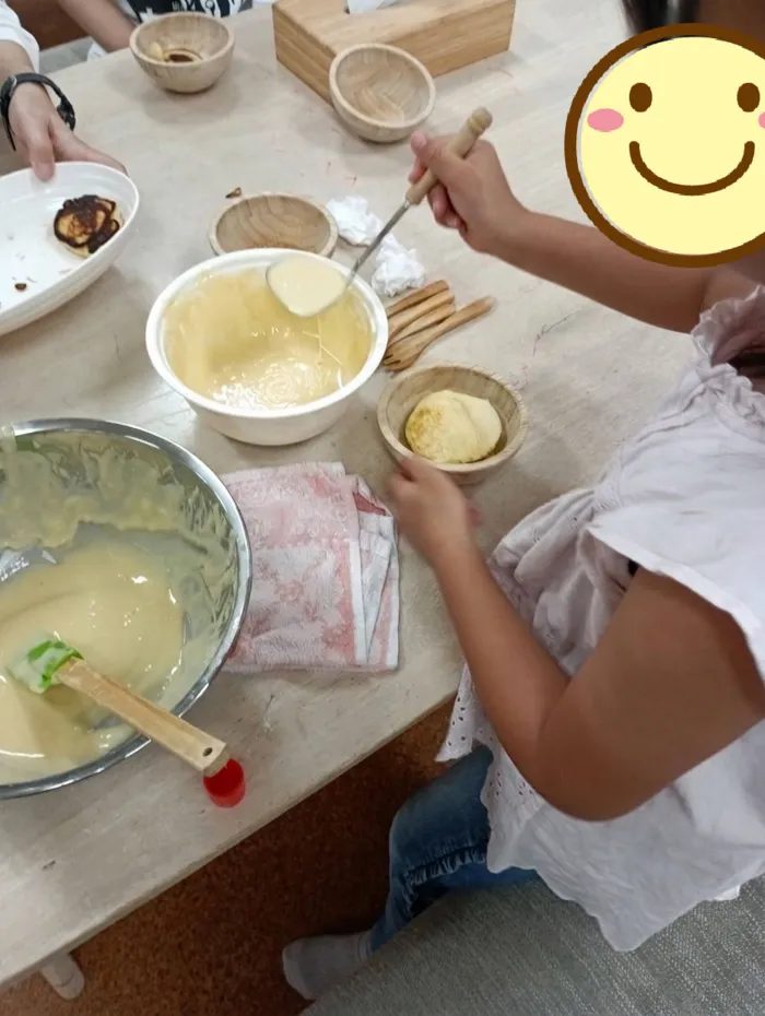 ボウルでパンケーキの生地を混ぜる手元と材料が並ぶテーブル