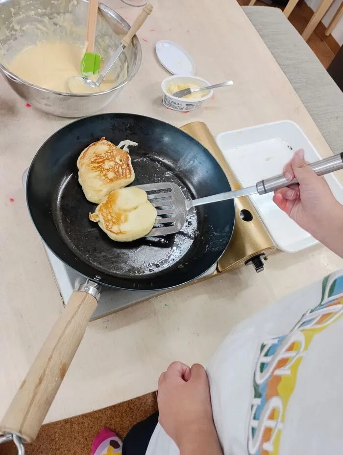 お誕生日会のおやつにフライパンで焼いているパンケーキ