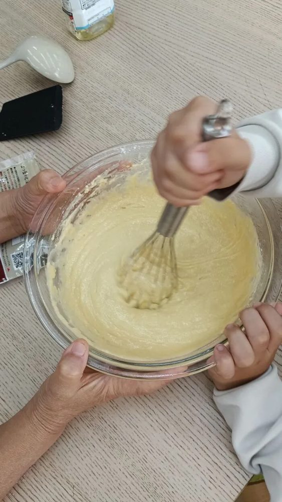 ボウルを押さえながら泡立て器でホットケーキの生地を混ぜる手元