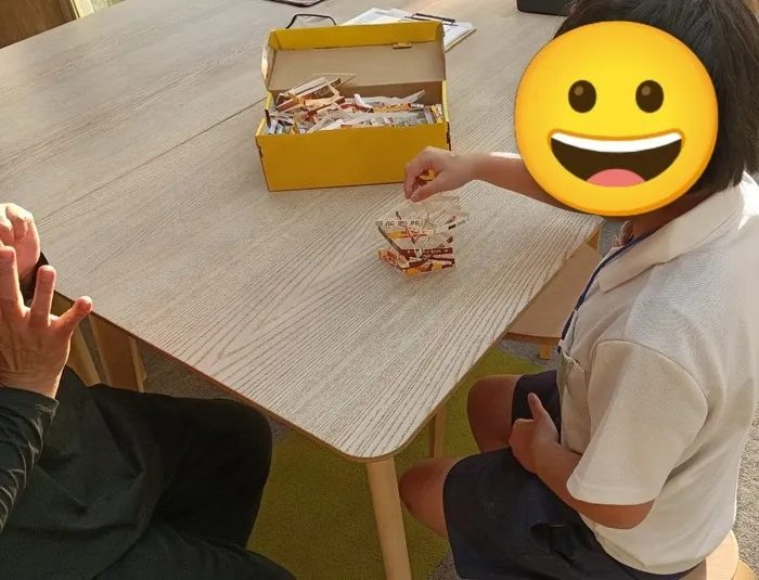 机の上で牛乳パックの輪っかをそっと積み上げる子どもの手元