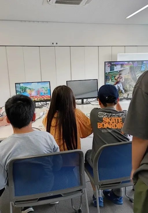 ゲーム交流会の会場で画面に向かってゲームをする子どもたちの後ろ姿