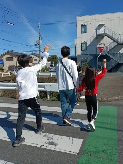 避難訓練で職員と一緒に手を挙げて横断歩道を渡る子どもたちの後ろ姿
