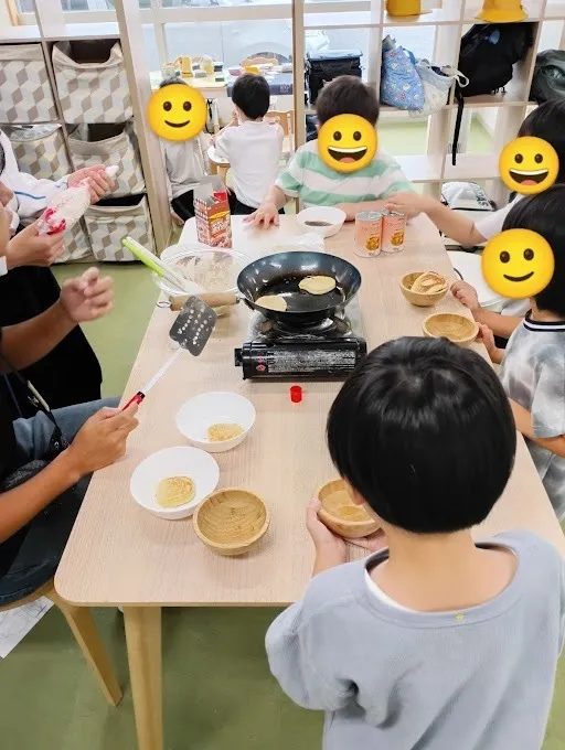 ホットプレートでホットケーキを焼きながらテーブルを囲む子どもたち