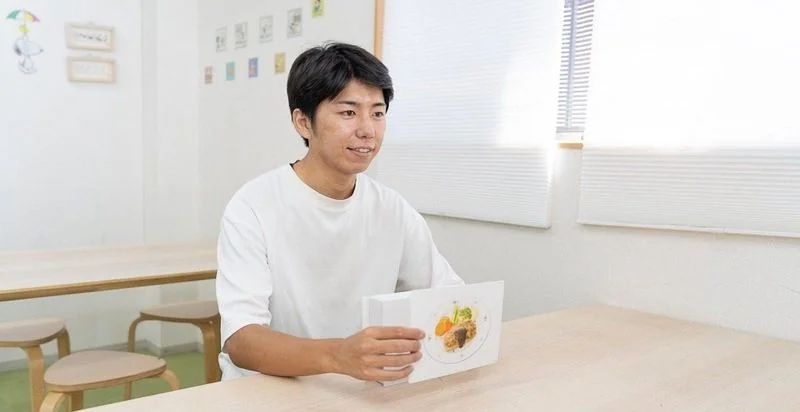 ぐりーん天理本店の児童指導員 久保崇太郎が絵カードを使って支援している様子